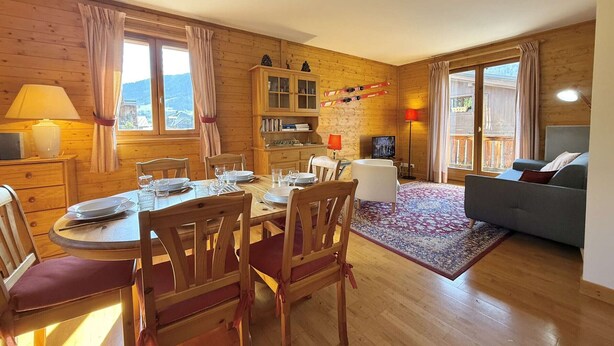A cozy wooden interior with a dining area, a sofa, and a TV. - Spacious 3-Room Apartment in Praz-Sur-Arly, Sleeps 6, Central Location, Parking Included (Praz-sur-Arly)