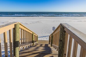 A wooden boardwalk leading to a sandy beach with ocean views.