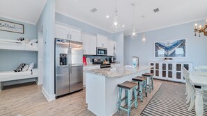 A modern kitchen with white cabinets, stainless steel appliances, and a central island with stools. - REEL RETREAT-LAGOON FRONT PRIVATE COTTAGE, EXTRA AMENTIES, BEACH ACCESS, LOTS OF OUTDOOR FURNITURE (Gulf Shores)