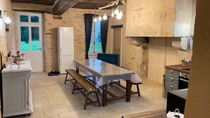 A rustic kitchen with a wooden table, bench, and a refrigerator. - Charming XIXth Century Château near Le Mans with Pool and Park (Parennes)