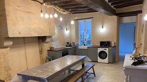 A kitchen with a large table, a washing machine, and a window. - Charming XIXth Century Château near Le Mans with Pool and Park (Parennes)