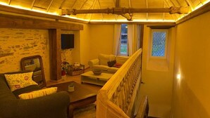 A cozy living room with a stone wall, a wooden staircase, and a comfortable seating area. - Charming XIXth Century Château near Le Mans with Pool and Park (Parennes)