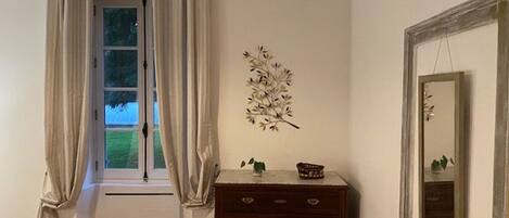 A room with a window, a dresser with drawers, and a wall-mounted decoration.