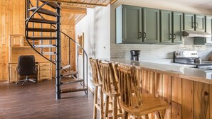 A kitchen with wooden cabinets, a spiral staircase, and a bar area with stools.