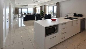 Una cocina moderna con una isla central, comedor y vista al mar.