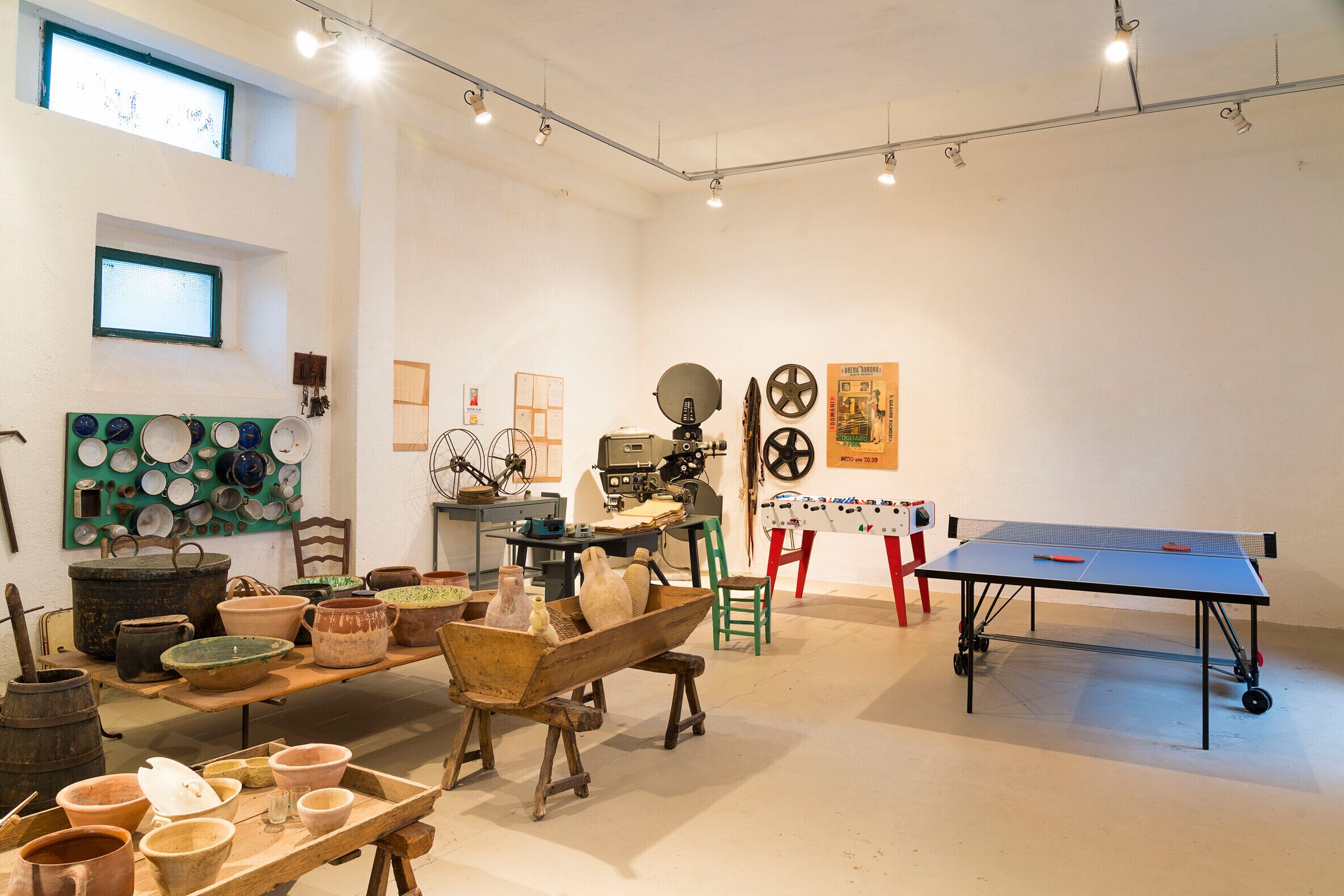 A room with a ping pong table, pottery, and a vintage sewing machine.