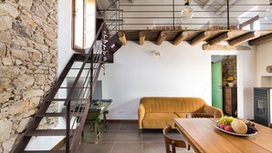 A modern interior with a stone wall, wooden staircase, a sofa, and a dining table with fruit. - Charming house with shared pool - Don Carlo (Buseto Palizzolo)