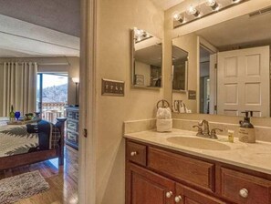 Un baño con un espejo grande, tocador de madera y vistas a un balcón.