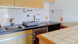 A kitchen with wooden cabinets, a dishwasher, a coffee maker, and a tiled backsplash. - A/C T2, WIFI, Private Parking, Close to Beach - Bormes les Mimosas (Bormes-les-Mimosas)