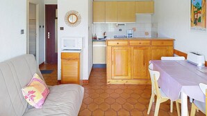A compact living space with a kitchenette, a dining area, and a sofa with a cushion. - A/C T2, WIFI, Private Parking, Close to Beach - Bormes les Mimosas (Bormes-les-Mimosas)