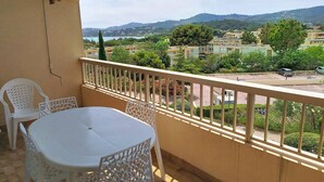 A balcony with a table and chairs, overlooking a residential area with houses and greenery. - A/C T2, WIFI, Private Parking, Close to Beach - Bormes les Mimosas (Bormes-les-Mimosas)