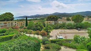 A residential area with buildings, a parking lot, and a view of the sea and hills. - A/C T2, WIFI, Private Parking, Close to Beach - Bormes les Mimosas (Bormes-les-Mimosas)