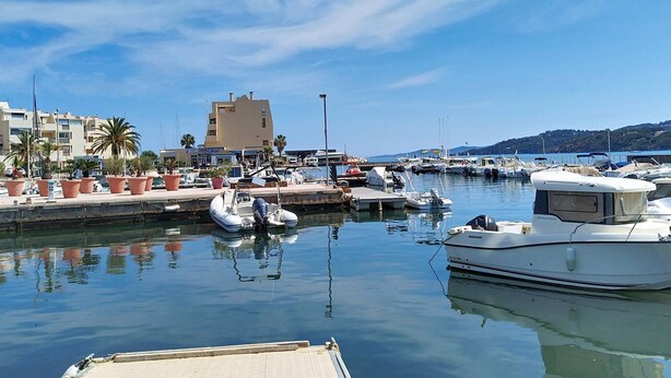 A marina with boats docked, a building with a flat roof, and palm trees. - A/C T2, WIFI, Private Parking, Close to Beach - Bormes les Mimosas (Bormes-les-Mimosas)