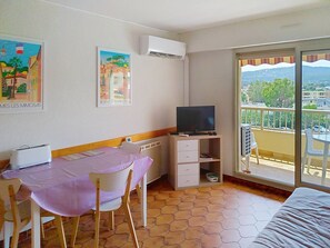 Une chambre avec un lit, un téléviseur posé sur un meuble, une table avec une chaise et un balcon avec vue.