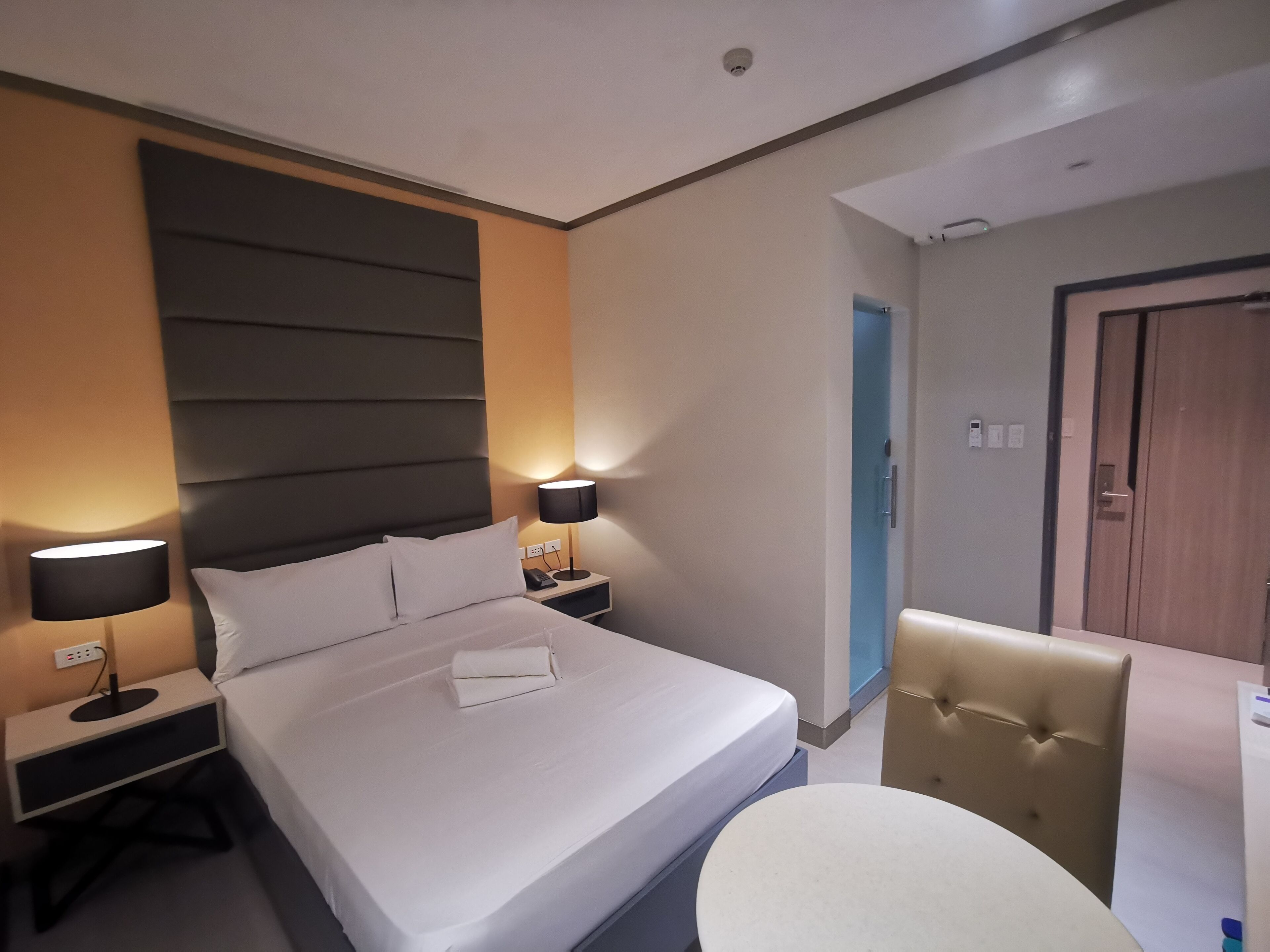 A hotel room with a bed, bedside tables, a chair, and a lamp.