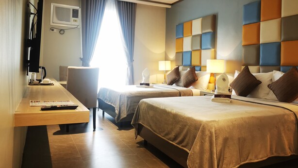 A hotel room with two beds, a desk with a chair, a coffee machine, and a window with curtains. - Yes Hotel Pandi Bulacan (Pandi)