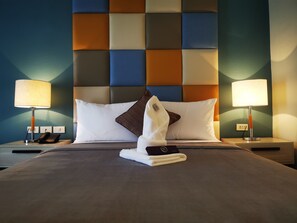 A neatly made bed with white and brown pillows, a folded towel, and two bedside lamps on a nightstand. - Yes Hotel Pandi Bulacan (Pandi)