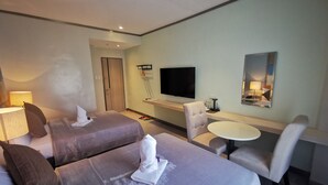 A hotel room with two beds, a desk, a chair, a TV, and a mirror. - Yes Hotel Pandi Bulacan (Pandi)