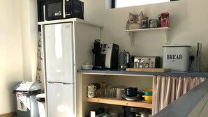 Et kompakt køkken med køleskab, mikroovn, kaffemaskine og en brødrister på bordpladen.