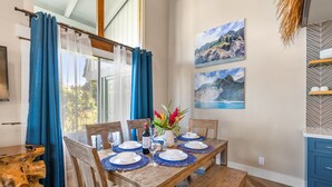 Comedor con una mesa de madera dispuesta para cuatro, individuales azules y un florero con flores.