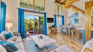 Un espacio habitable amplio con una mesa grande, asientos cómodos, una zona de comedor y vistas a zonas verdes al exterior.