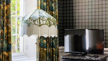 A room with a sofa, a television on a cabinet, and curtains with a floral pattern.