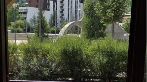 A view through a window of a building with a parking lot and a grassy area. - studio near track and shopping mall (La Salle-les-Alpes)