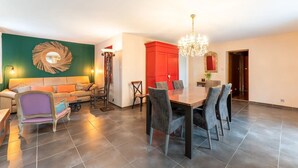 A modern living room with a sofa, dining table, and chairs. There is a chandelier above the table. - Les dames de Mollégès, at the gateway to the Alpilles, 10 minutes from St Rémy de Provence (Mollégès)