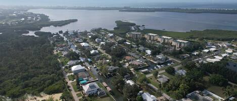 An aerial view of a coastal residential area with houses, a marina, and a large body of water.