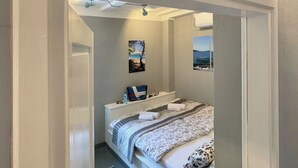 A bedroom with a bed, a nightstand, a window with a view, and a sign above the door.