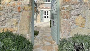 A stone archway leading to a building with a door and windows.