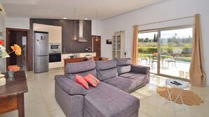 A modern living room with a grey sofa, a dining table, and a kitchen in the background. - Son Alcaines Petit 249 cosy finca with private pool, terrace, barbecue and WiFi (Sineu)