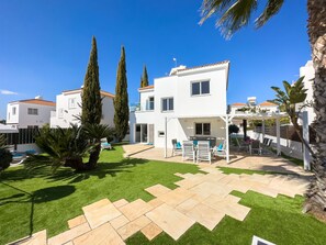 Een moderne villa met een terras, buitenmeubilair en een verzorgd gazon.