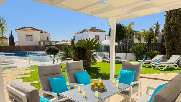 Un patio con mobiliario exterior, una piscina y vistas a casas vecinas.