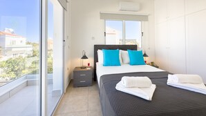 Un dormitorio moderno con una cama grande, dos mesitas de noche, una ventana con vistas y un balcón.