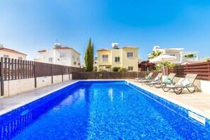 A swimming pool with lounge chairs and a wooden fence.