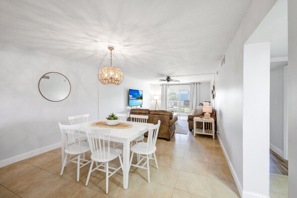 A bright, spacious room with a dining table and chairs, a sofa, a TV, and a ceiling fan. - Gorgeous Cocoa Beach Getaway w/ Pool, Tennis & Steps from the Pier! (Cocoa Beach)