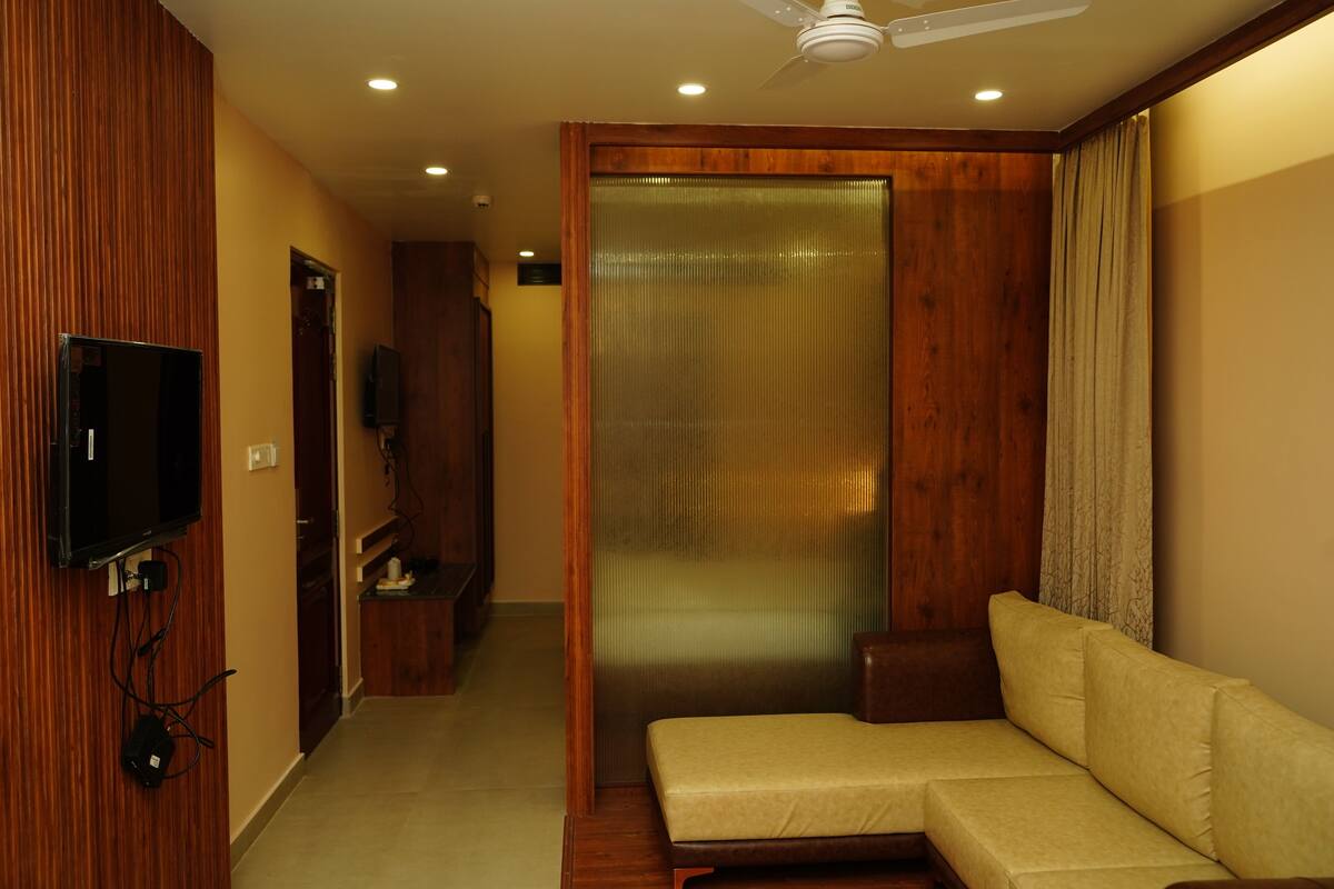 A modern living room with a sofa, a television mounted on the wall, and a ceiling fan.