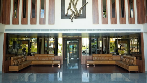 A lobby with a large reception desk, two seating areas, and a modern art piece above the desk. - Mansha Palace (Port Blair)