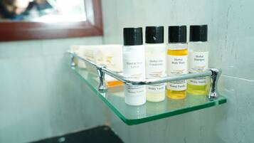Une étagère de salle de bain contenant divers produits de toilette, notamment une lotion pour les mains et le corps, un après-shampoing aux plantes, un gel douche aux plantes et un shampoing aux plantes.
