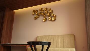 A room with a beige sofa, a small round table, and a wall-mounted decorative gold piece.