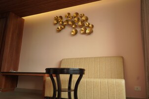 A room with a beige sofa, a small round table, and a wall-mounted decorative gold piece.