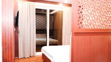 A hotel room with a bed, curtains, and a decorative wooden partition.