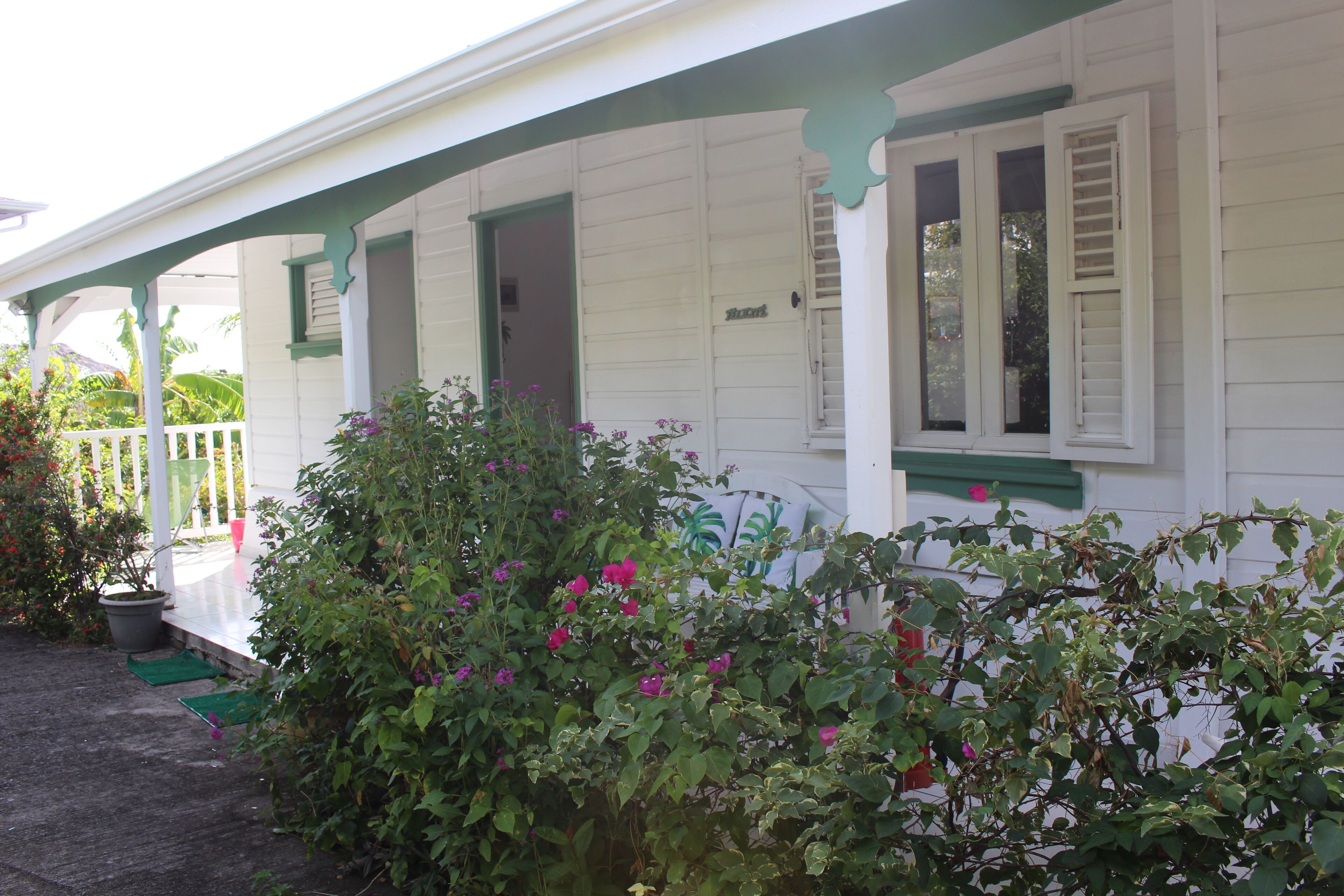 A white building with green trim and a covered porch.