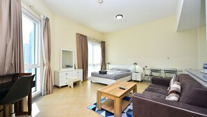 A modern hotel room with a bed, bedside tables, a desk, a sofa, and a view of the city. - Alia -Bright furnished studio near metro (Dubai)