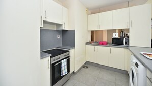 A compact kitchen with a stove, oven, microwave, and washing machine. - Alia -Bright furnished studio near metro (Dubai)