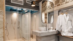 A modern bathroom with a glass-enclosed shower, a white sink, and a mirror above the sink. - Chateau Anax Hotel (Rhodes)