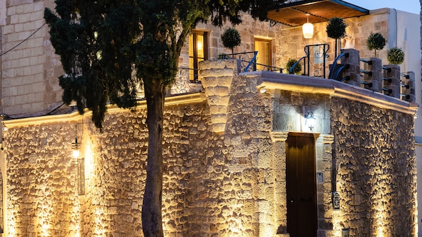 A stone building with a wooden door, a staircase, and a tree in front. - Chateau Anax Hotel (Rhodes)