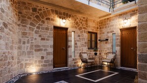 A stone-walled lobby with two wooden doors, a small table with chairs, and a decorative rug. - Chateau Anax Hotel (Rhodes)