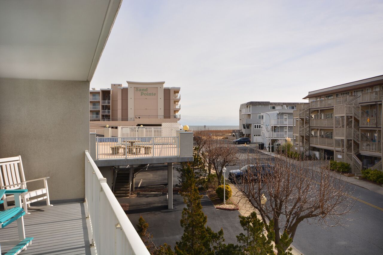 A hotel with a balcony, a parking area, and a view of the beach.